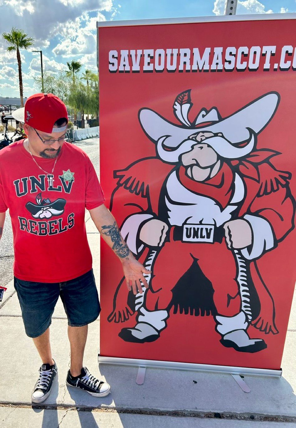 A fan beside a saveourmascot.com banner